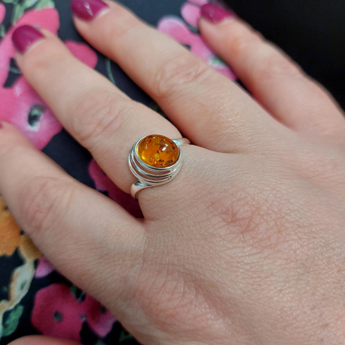 Adjustable ring in sterling silver and cognac Baltic amber with swirl details.