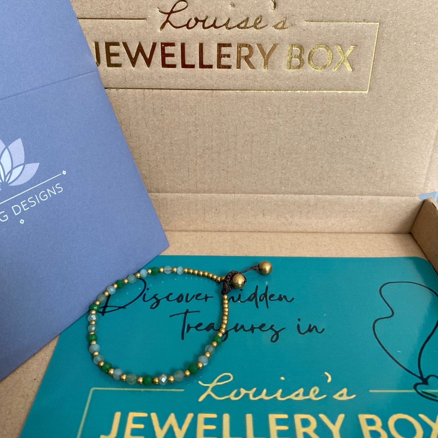 Green aventurine crystal bracelet for energy resting on a teal box.