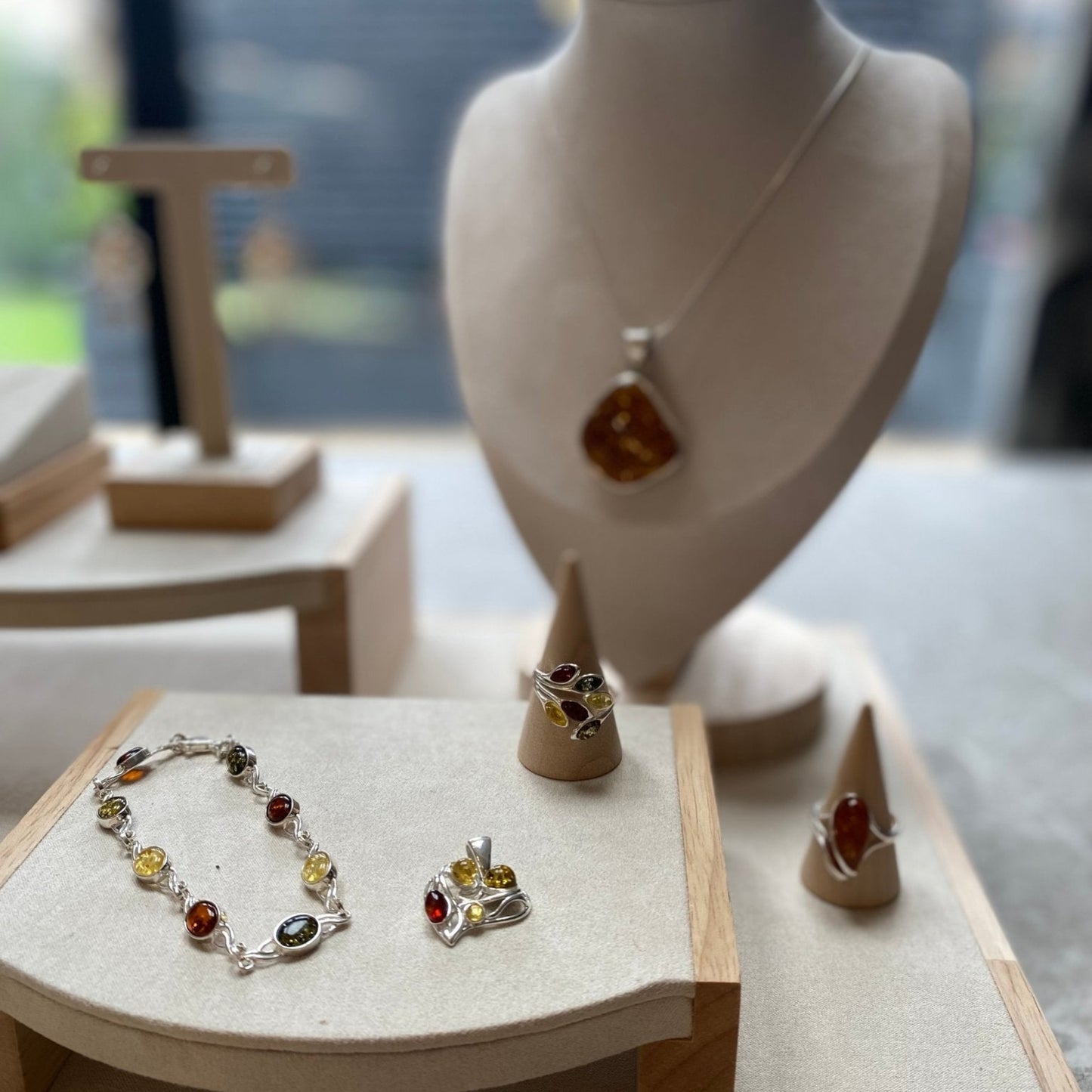Celtic inspired link bracelet in sterling silver with mixed baltic amber stones on a jewelry display.