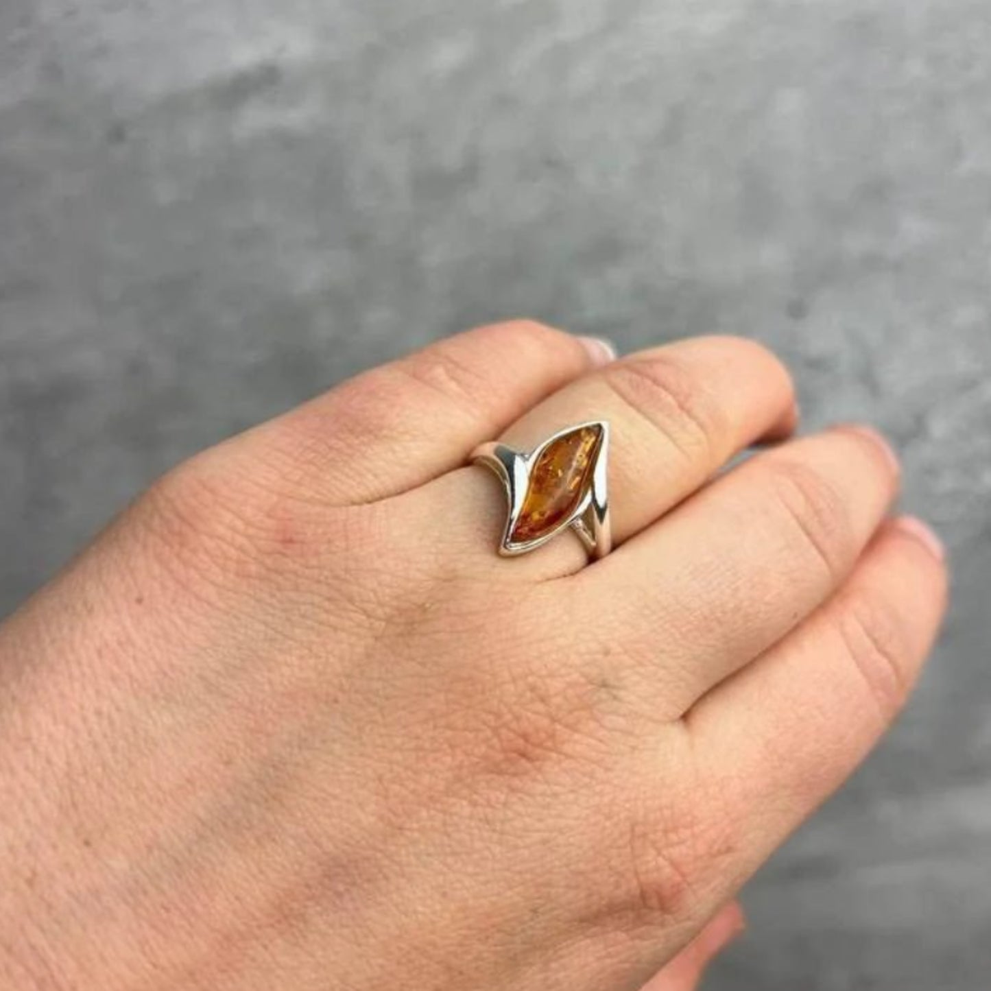 Adjustable cognac Baltic amber ring in sterling silver with leaf-shaped amber stone.