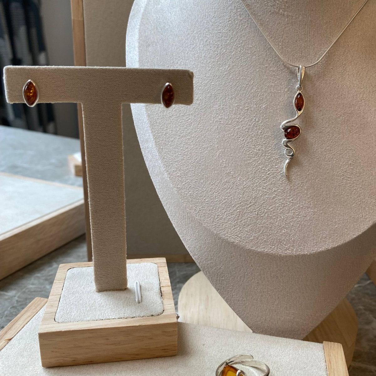 Modern snake pendant in sterling silver with cognac Baltic amber by LuksusBaltic, displayed with matching earrings and ring.