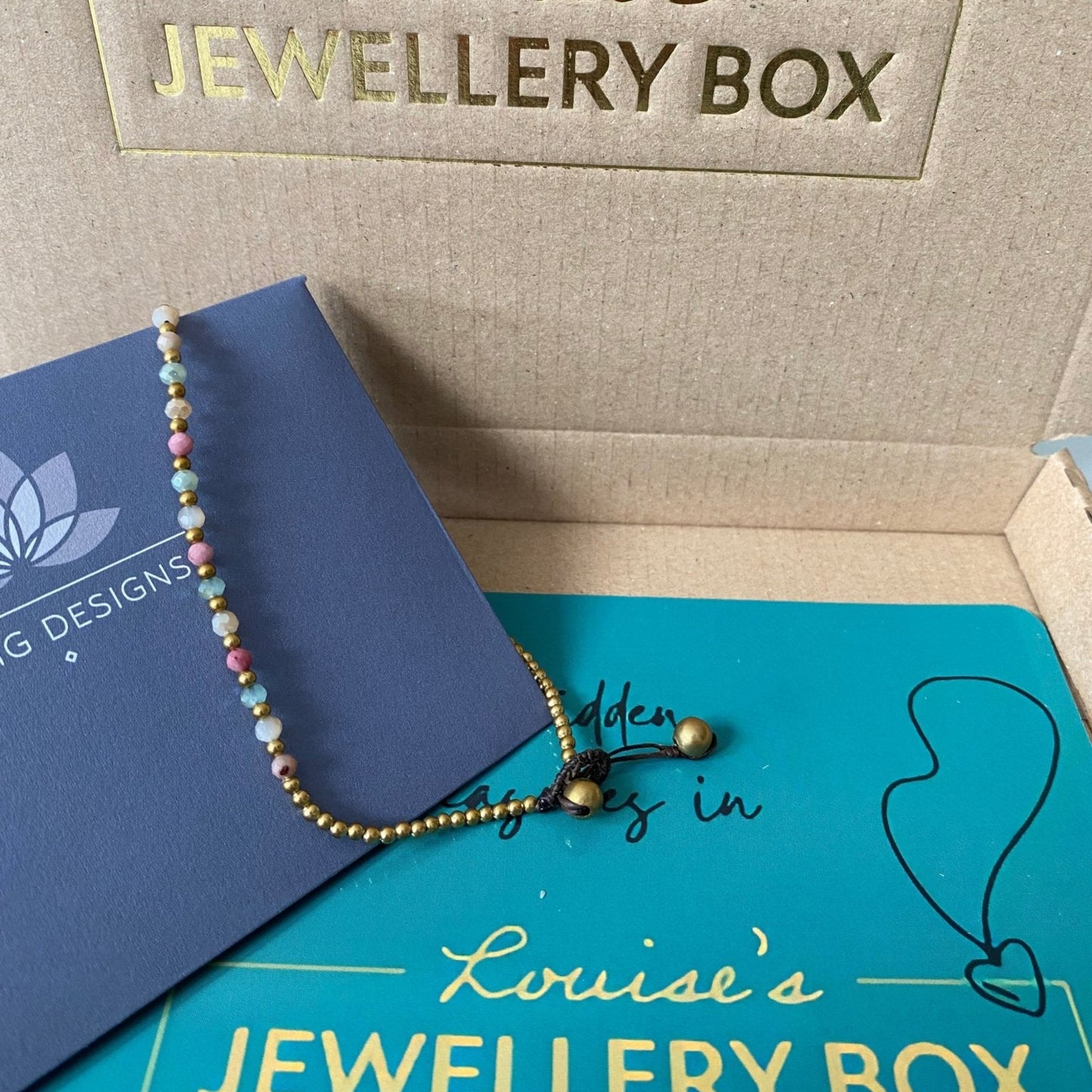 Beaded rhodonite crystal healing anklet for balance, with gold-tone accents and a knotted adjustable closure.