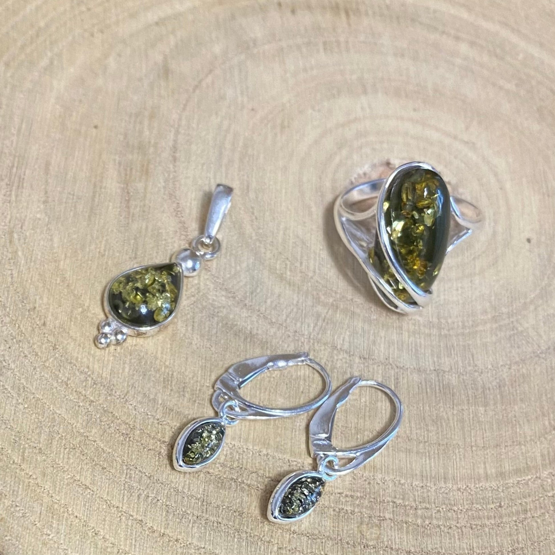 Green Baltic amber teardrop pendant in sterling silver showing natural inclusions with matching earrings and ring
