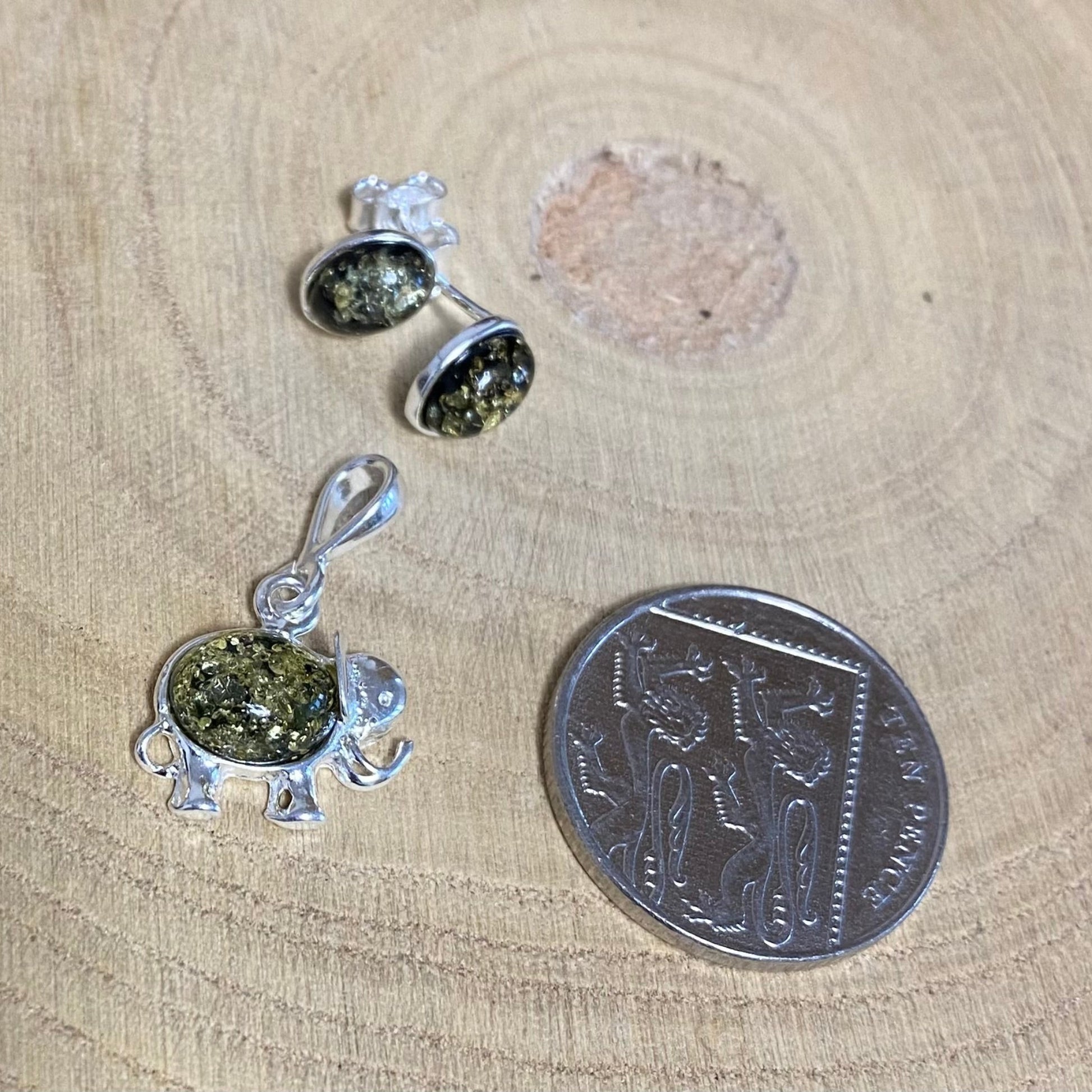 Close-up of green Baltic amber elephant pendant in sterling silver setting with matching earrings

