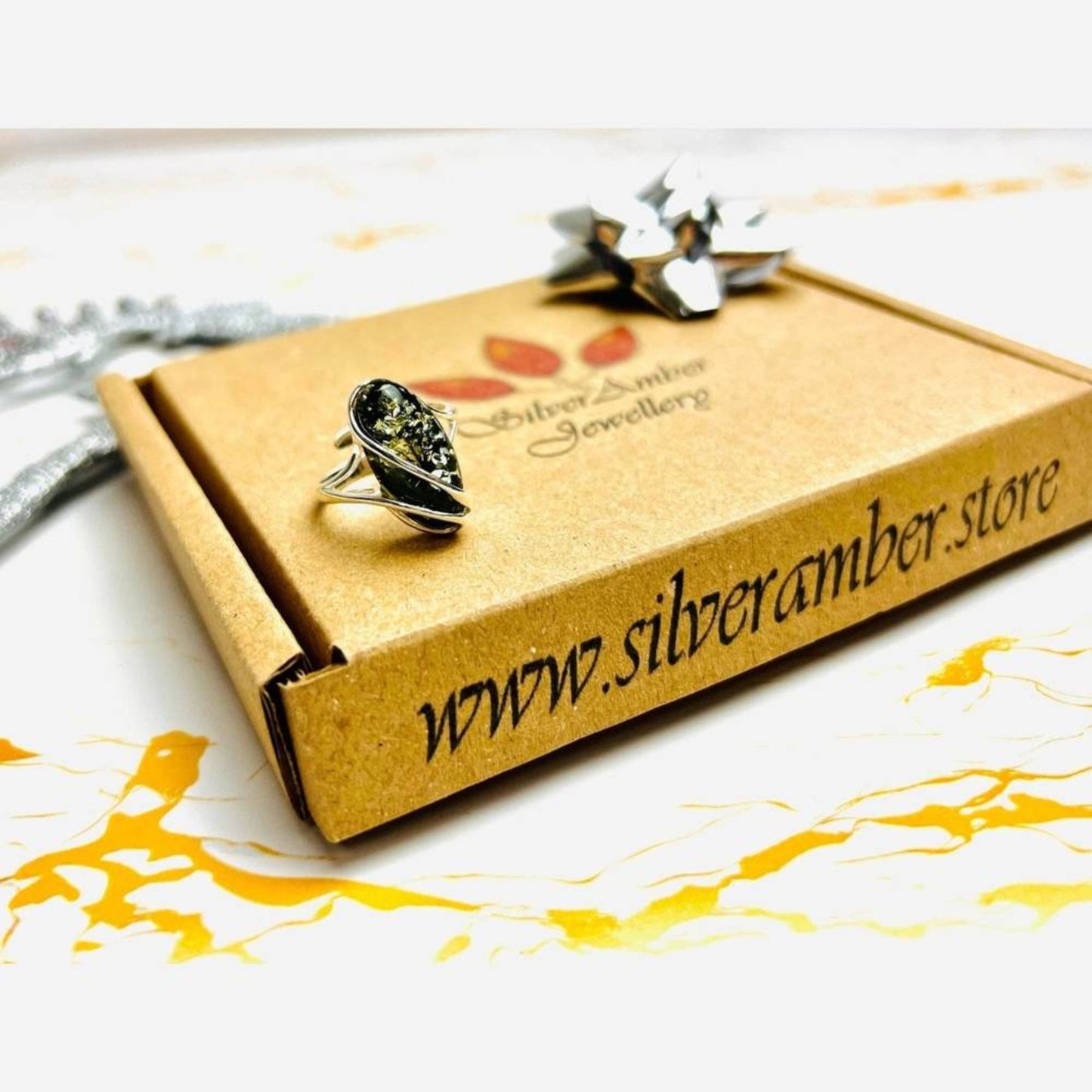 Green Baltic amber adjustable ring in sterling silver on Louise's Jewellery Box packaging

