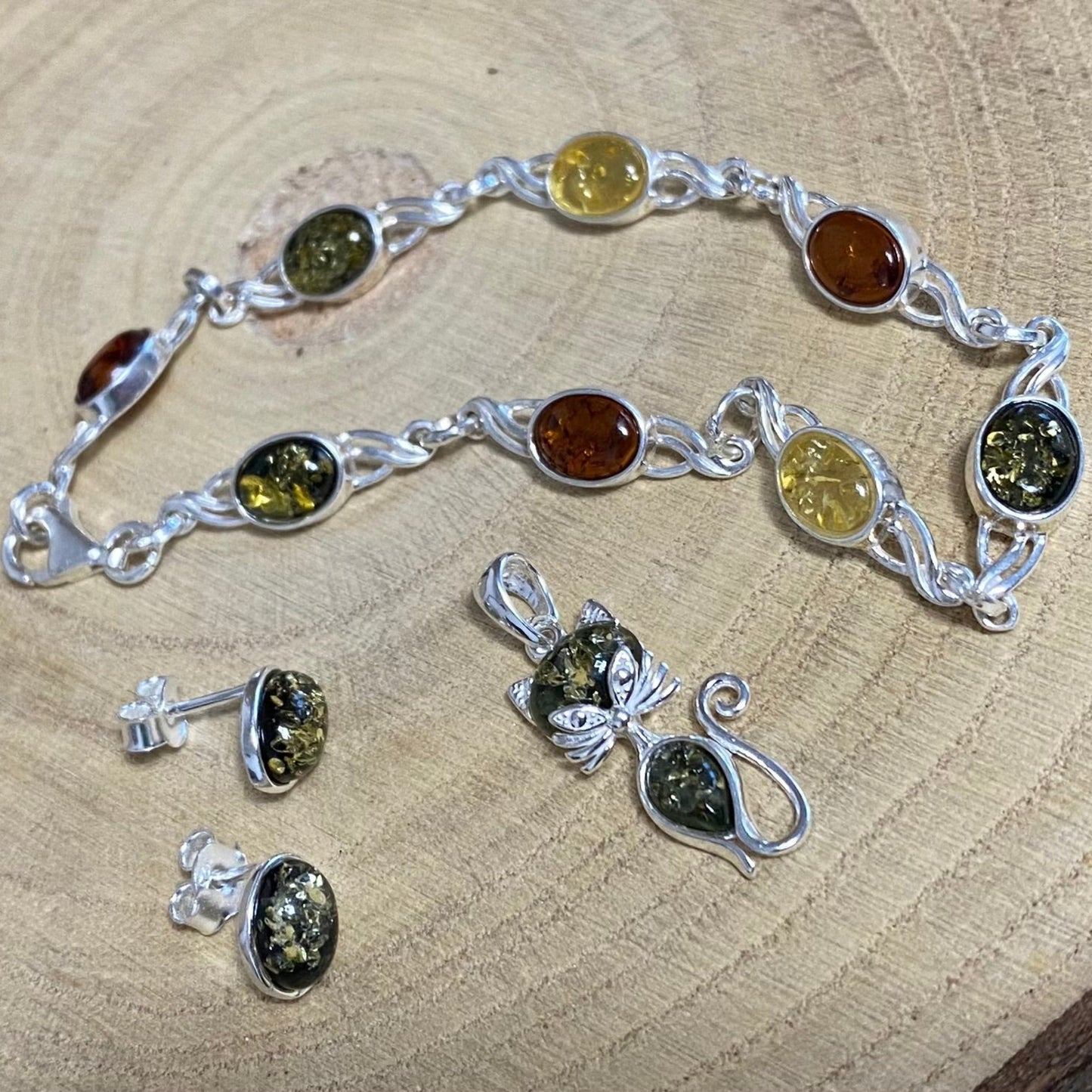 Oval stud earrings in sterling silver with green Baltic amber detail view and matching pendant and bracelet
