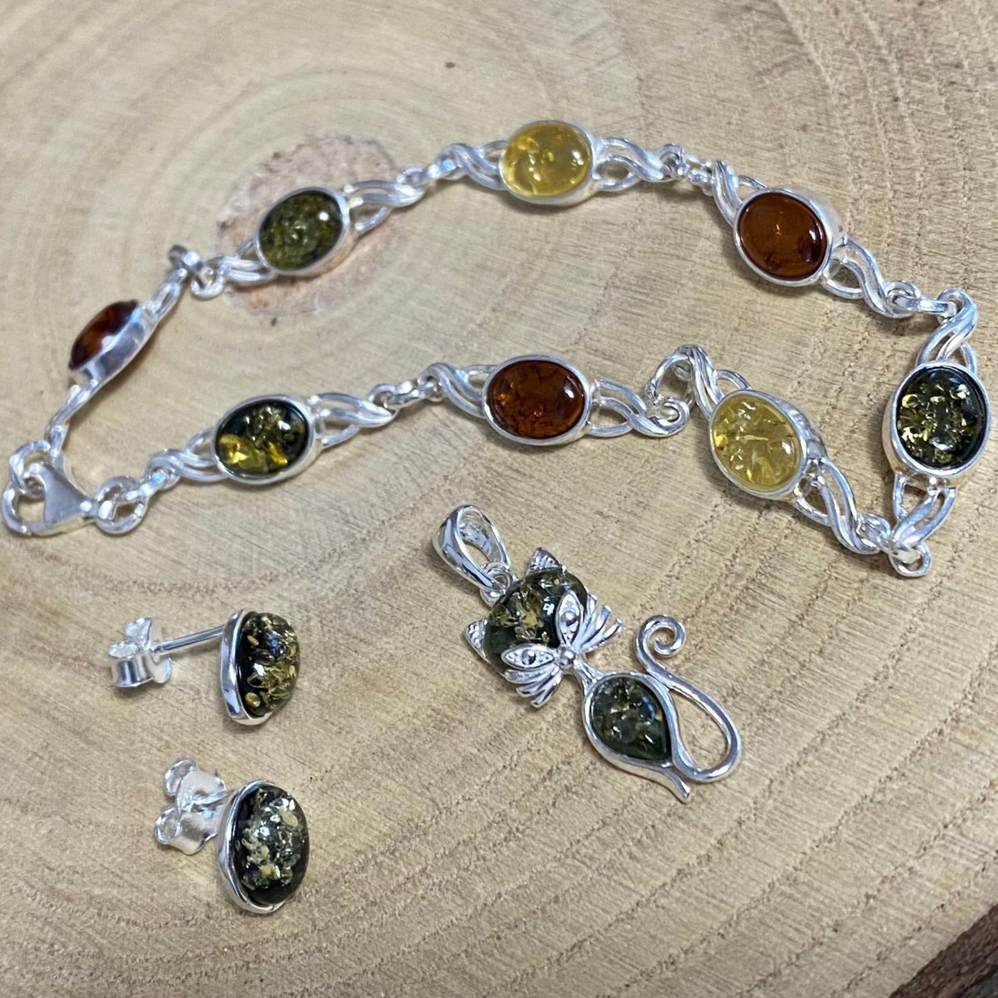 Oval stud earrings in sterling silver with green Baltic amber detail view and matching pendant and bracelet
